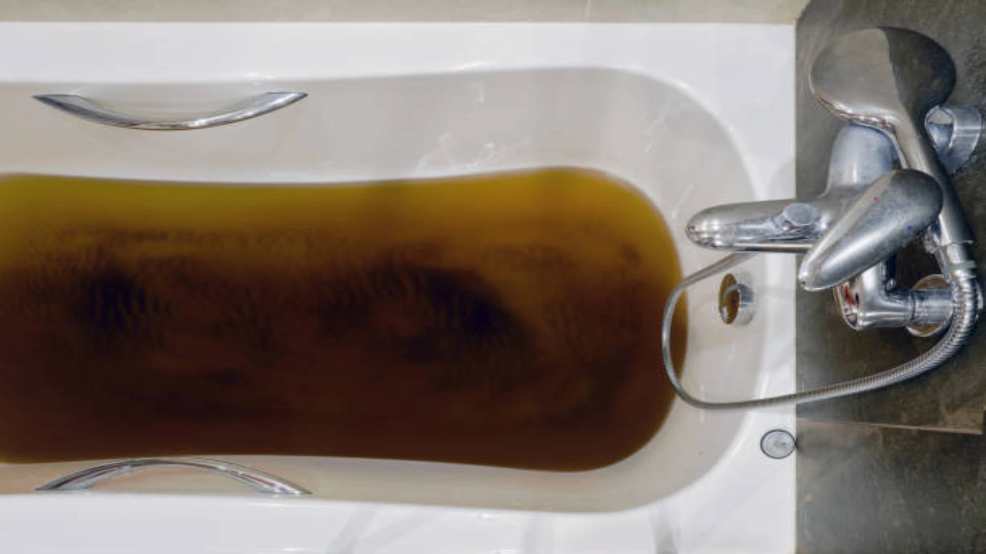 A close-up of a clogged shower drain with slow-draining water, emphasizing the importance of early maintenance.